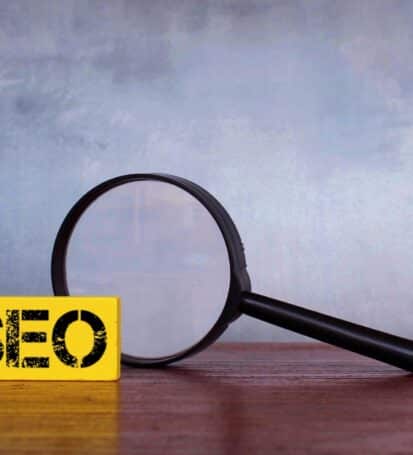 Magnifying glass and wooden cube with text SEO
